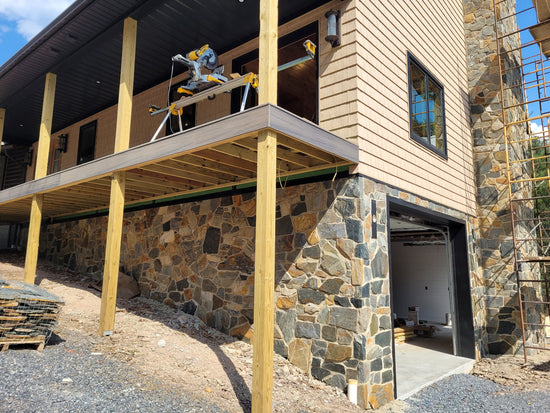 Building exterior with stone wall and wooden deck under construction